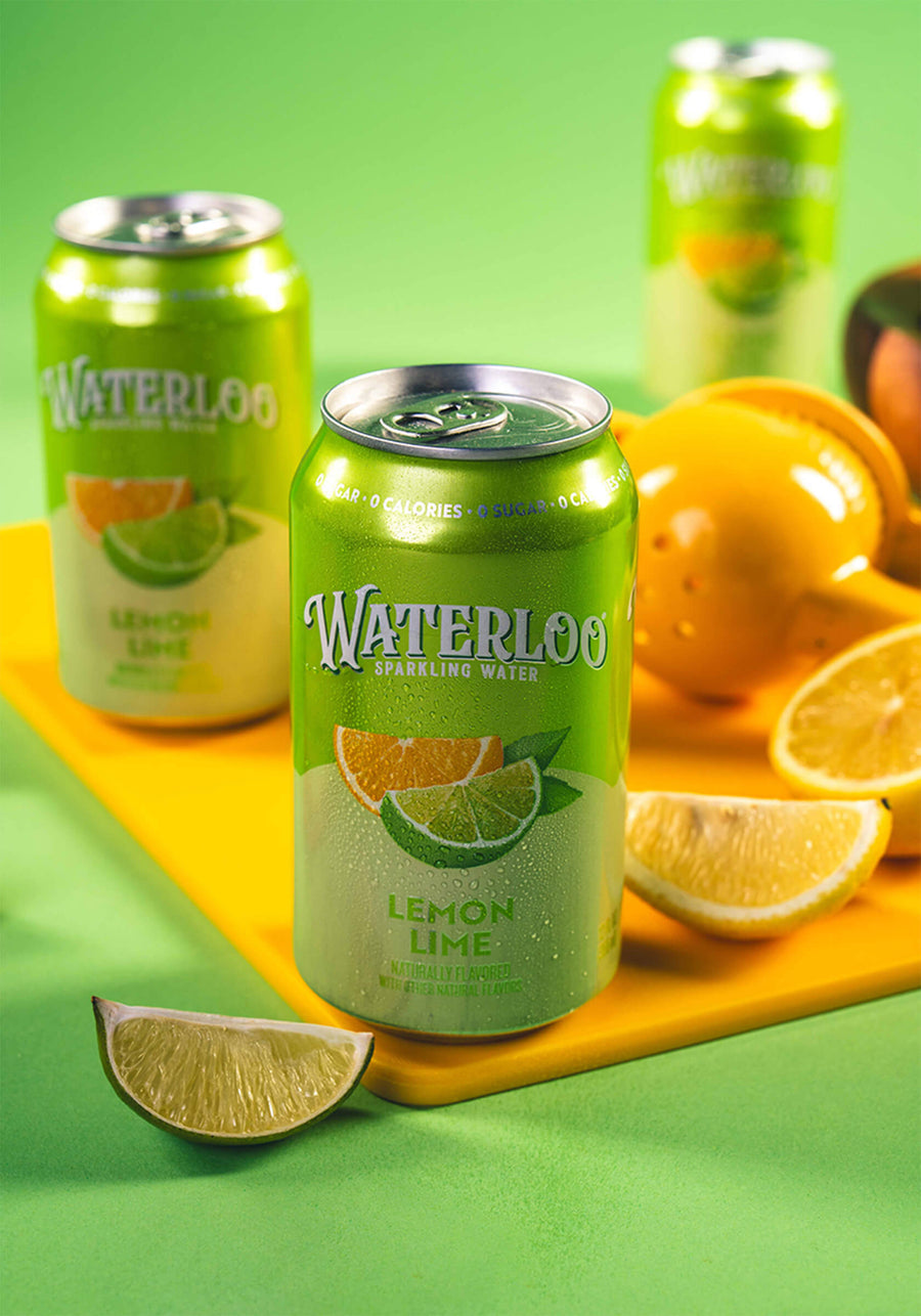 A refreshing can of Waterloo Lemon Lime sparkling water surrounded by fresh lemon slices on a vibrant green background.