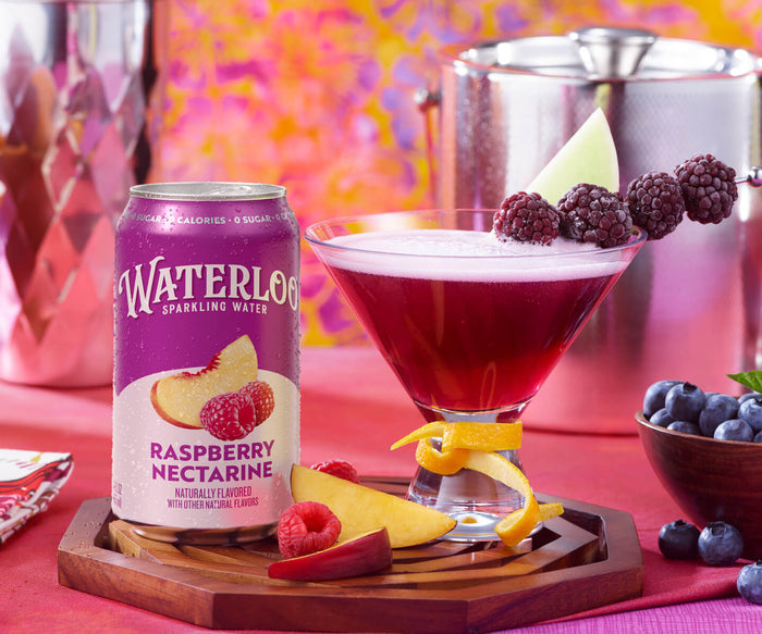 Refreshing Raspberry Nectarine Waterloo sparkling water with a cocktail glass, garnished with berries and fruit.