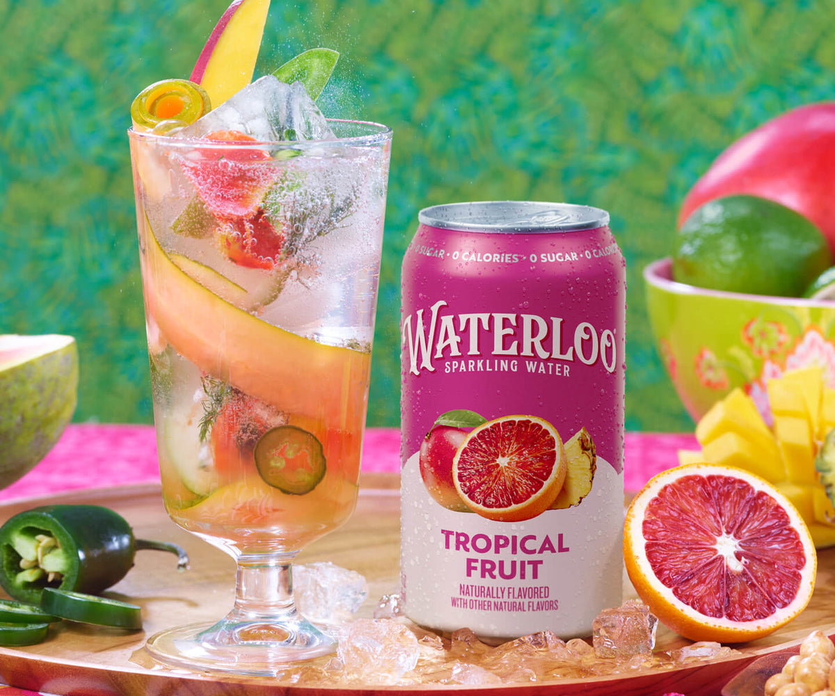 A refreshing glass of Waterloo Tropical Fruit sparkling water, garnished with fresh fruit and accompanied by a vibrant background.