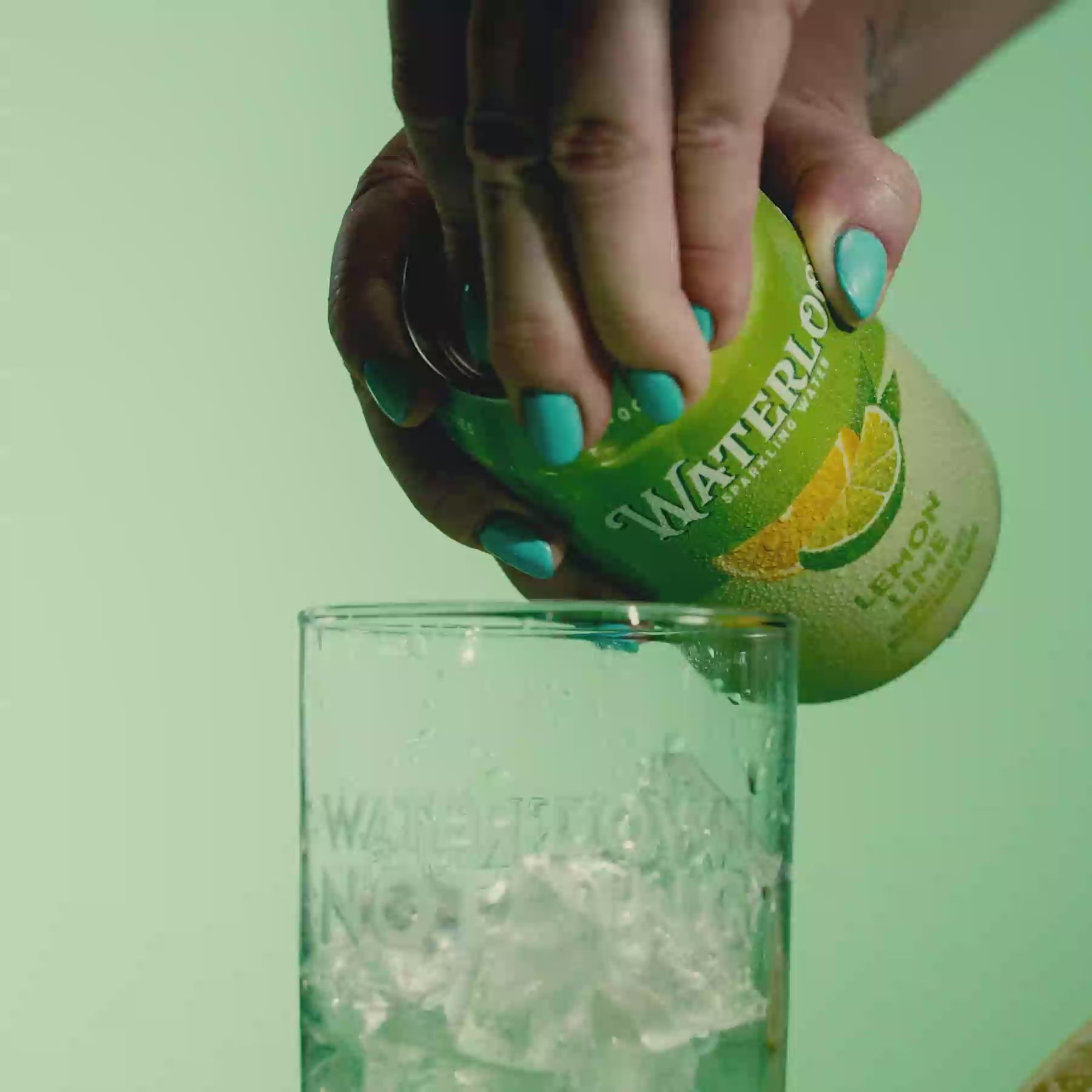 Person opening a can of Lemon Lime sparkling water into a glass filled with ice.