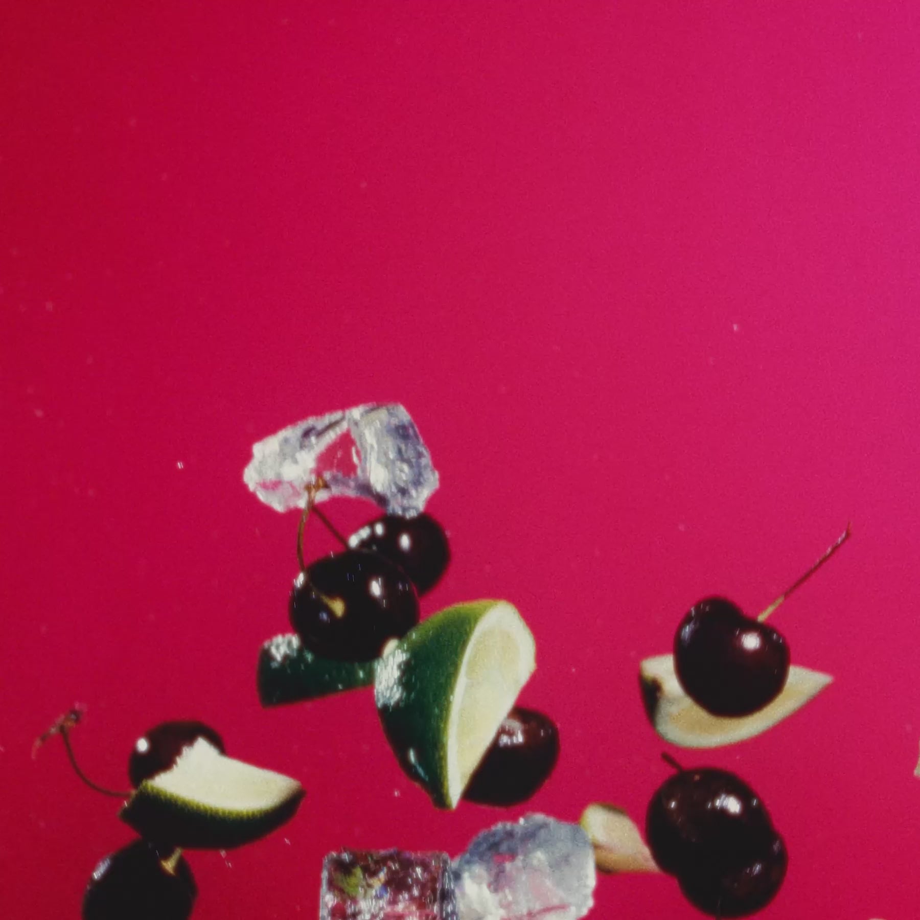 Fresh ingredients for Cherry Limeade, featuring limes, cherries, and ice against a vibrant pink background.